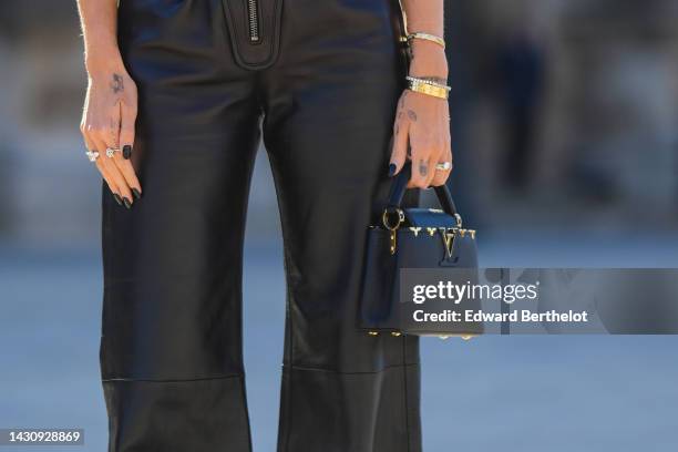 Chiara Ferragni wears high waist black shiny leather flared pants from Louis Vuitton, a black shiny leather handbag from Louis Vuitton, a large...