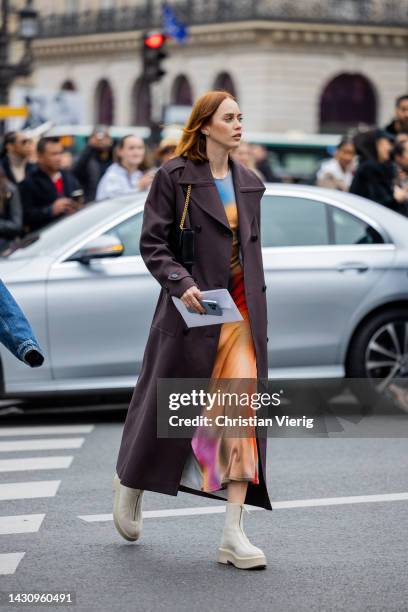 Guest wears double breasted coat, dress with batik print outside Thom Browne during Paris Fashion Week - Womenswear Spring/Summer 2023 : Day Eight on...