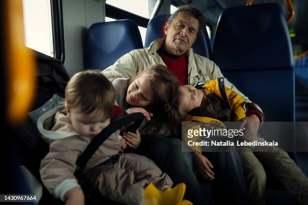 elderly man travel sleep in electric train with his children. man with three kids. - bambino treno foto e immagini stock