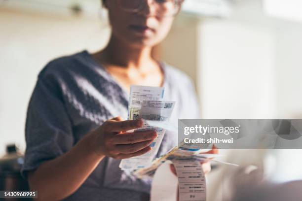 asian women examining the shopping receipt at home - austerity imagens e fotografias de stock