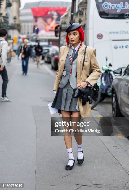 Kiwi Lee Han wears black beret, beige blazer, grey pleated skirt, two tone blazer, white socks, heels, tie, dog shaped bag outside Thom Browne during...