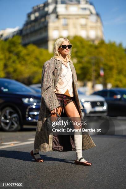 Caroline Daur wears black sunglasses from Miu Miu, a gold large chain necklace, a beige and white checkered print pattern wool polo shirt, brown and...