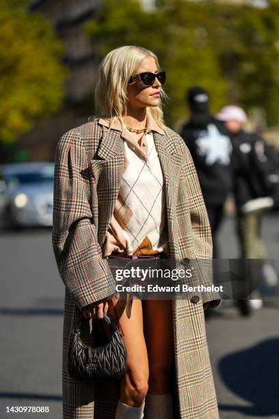 Caroline Daur wears black sunglasses from Miu Miu, a gold large chain necklace, a beige and white checkered print pattern wool polo shirt, brown and...