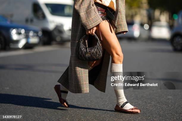 Caroline Daur wears a beige and white checkered print pattern wool polo shirt, brown and burgundy shiny leather shorts from Miu Miu, a beige with...