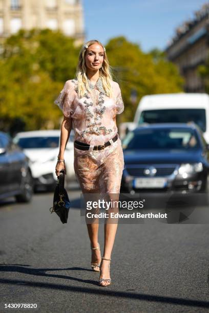 Leonie Hanne wears a white hair clips from Miu Miu, silver earrings, a white tulle with embroidered silver crystal details shorts sleeves knees dress...