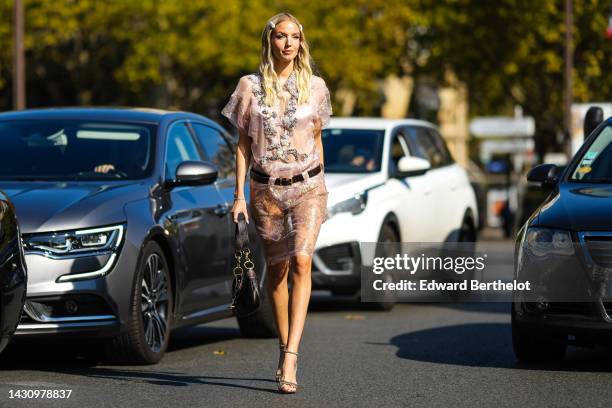 Leonie Hanne wears a white hair clips from Miu Miu, silver earrings, a white tulle with embroidered silver crystal details shorts sleeves knees dress...