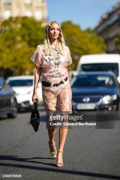 Leonie Hanne wears a white hair clips from Miu Miu, silver earrings, a white tulle with embroidered silver crystal details shorts sleeves knees dress...