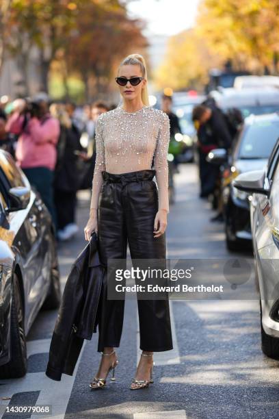 Poppy Delevingne wears black cat eyes sunglasses, a white tulle with embroidered crystal long sleeves body top from Miu Miu, high waist black shiny...