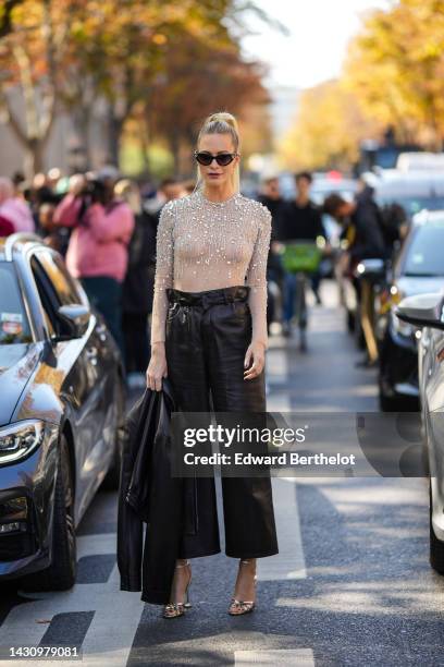 Poppy Delevingne wears black cat eyes sunglasses, a white tulle with embroidered crystal long sleeves body top from Miu Miu, high waist black shiny...