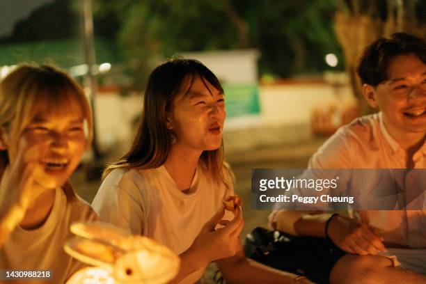 giovani amici e familiari asiatici che si divertono e mangiano la tradizionale mooncake durante la celebrazione del mid-autumn festival all'aperto - festival delle lanterne cinesi foto e immagini stock