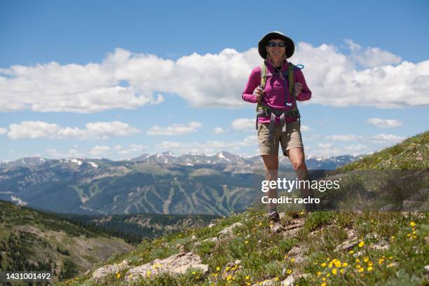 fit mature woman on a hike along the colorado continental divide. winter park and mary jane ski resort visible on the distant mountain behind. - mary jane ski stock pictures, royalty-free photos & images