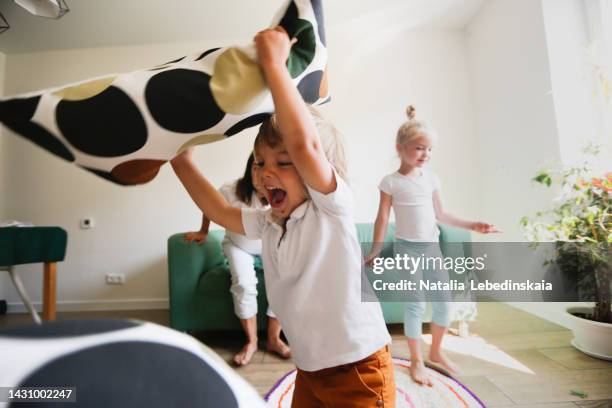 funny crazy children get mad and throw pillows living room. happy family moments - choas stock pictures, royalty-free photos & images