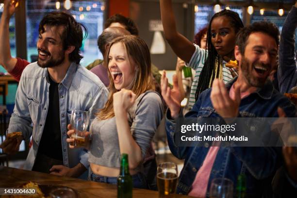 group of sports fans cheering and celebrating their team's victory at crowded sports bar - crowd cheering bar stock pictures, royalty-free photos & images