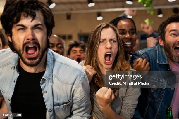 euphoric group of sports fans at crowded sports bar celebrating after their team scores a goal - chant stock pictures, royalty-free photos & images