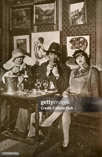 French painter and models in 1920s Paris in Montparnasse café 'La Rotonde'. Walls covered with artists' paintings. Bohemian ,literary and social life...