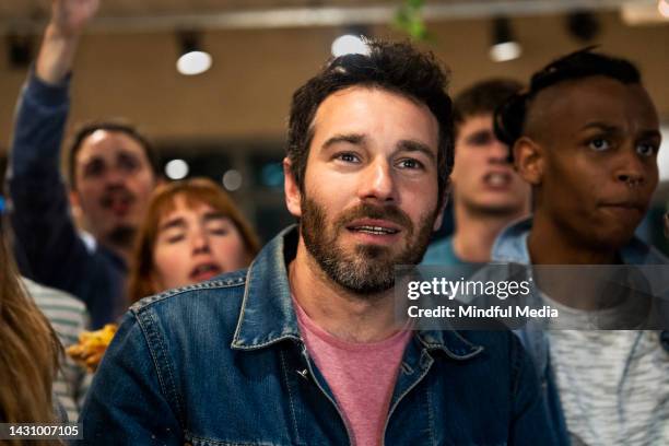 group of friends cheering for local team at sports bar - crowd cheering bar stock pictures, royalty-free photos & images