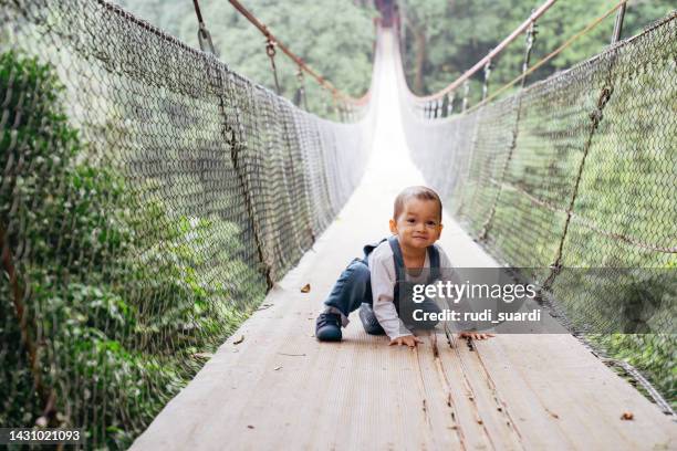 cute baby learning walking on the suspension bridge - alleen één jongensbaby stockfoto's en -beelden