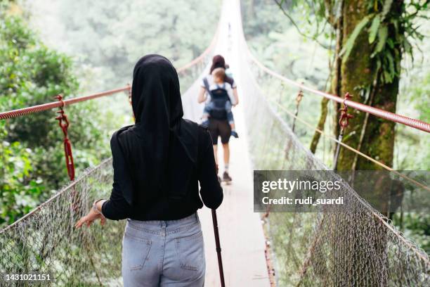 chinesische frau und muslimische freundin gehen gemeinsam auf der hängebrücke - wildnisgebiets name stock-fotos und bilder