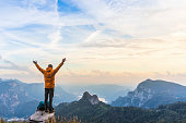 Happy hiker with raised arms on top of the mountain