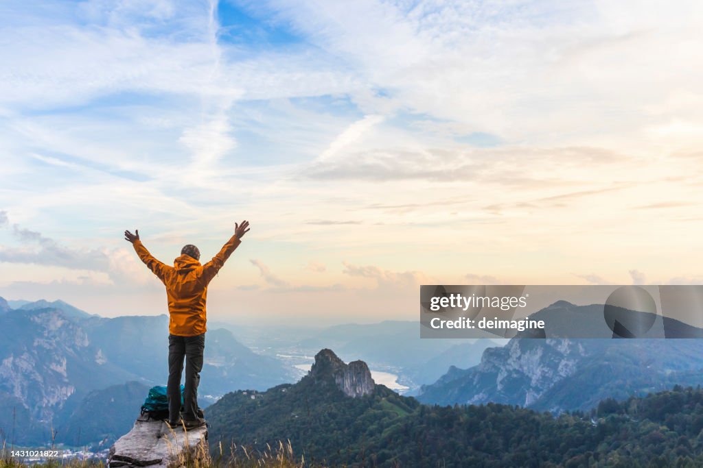Happy hiker with raised arms on top of the mountain