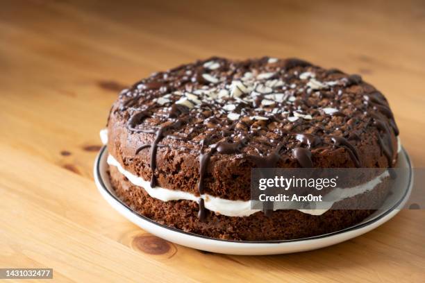 chocolate cake with cream on a wooden table - チョコレートケーキ ストックフォトと画像