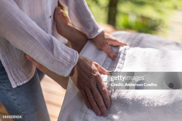 reiki therapist with but hands on a woman's feet - energy healing stock pictures, royalty-free photos & images