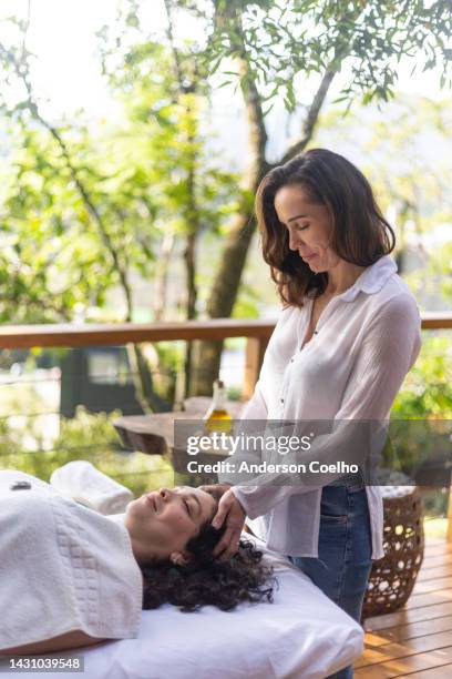 woman in reiki session with middle aged woman - energy healing stock pictures, royalty-free photos & images