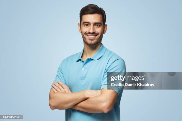 Portrait of young european man on blue background in polo shirt with crossed arms smiling at camera