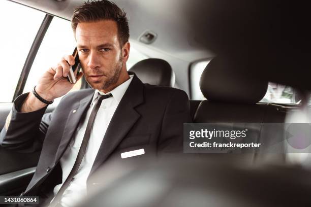 geschäftsmann in einem taxi, der die zeit überprüft - calling a cab stock-fotos und bilder