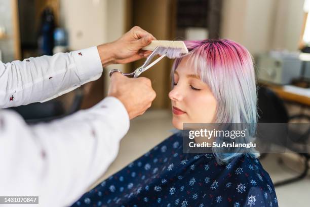 mujer joven con el pelo teñido cortándose el pelo en la peluquería - bangs fotografías e imágenes de stock