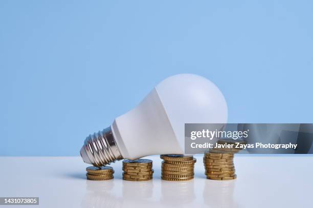 light bulb on stacked coins simulating financial growth graph - électricité photos et images de collection