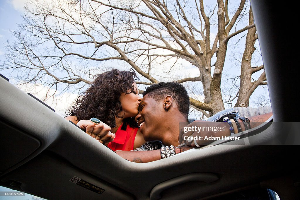 Two young friends hanging out next to a car.