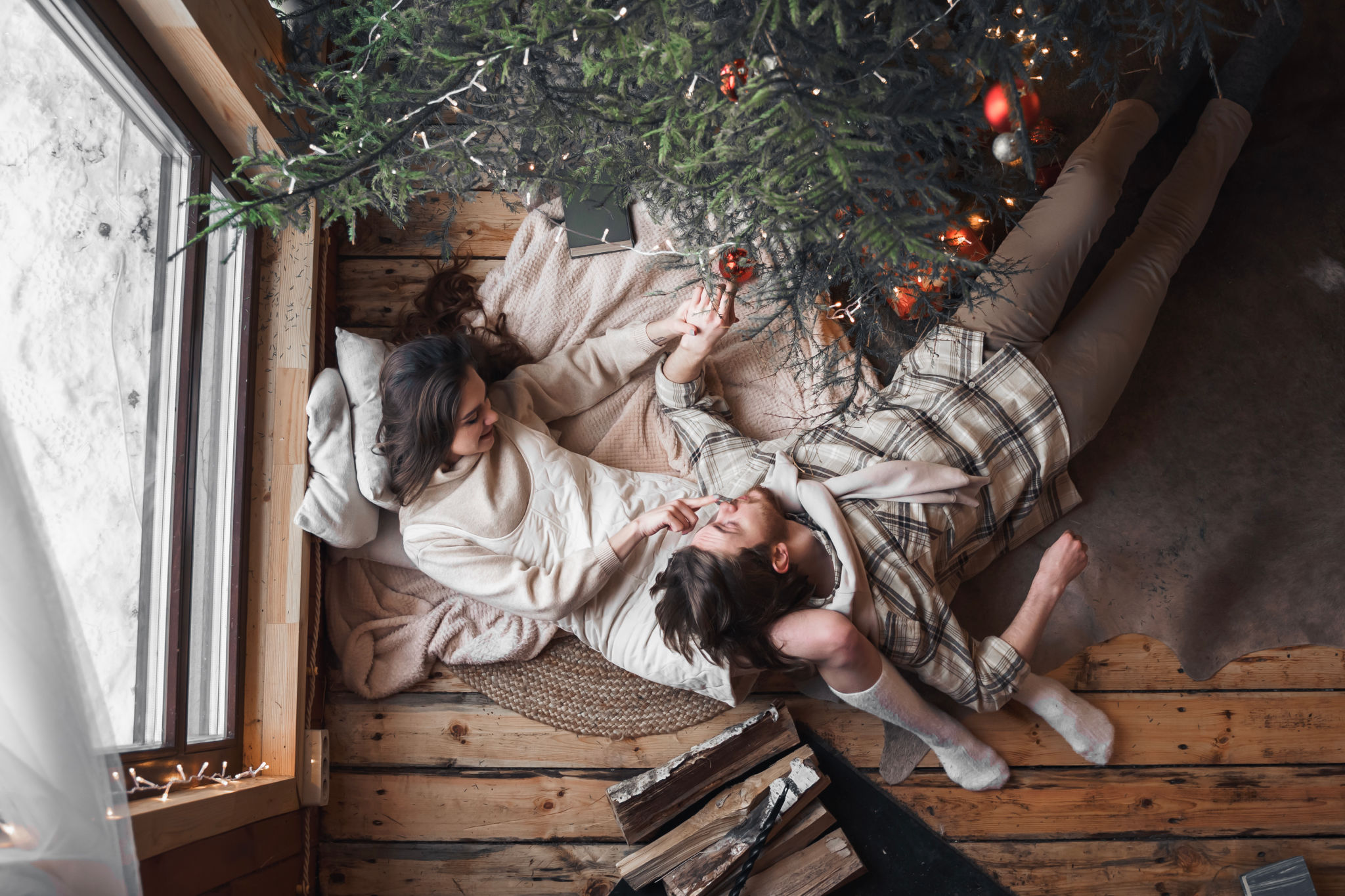 Young stylish love couple girl, guy lie on skin on floor in cozy wooden country house,chalet in winter forest. Celebrating new year eve. Gifts,family holiday.Romantic weekend.Decorated Christmas tree Young stylish love couple girl, guy lie on skin on floor in cozy wooden country house,chalet in winter forest. Celebrating new year eve. Gifts,family holiday.Romantic weekend.Decorated Christmas tree