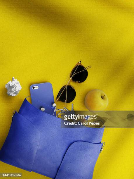 contents of woman  handbag in yellow background.top view. - sunglasses overhead fotografías e imágenes de stock
