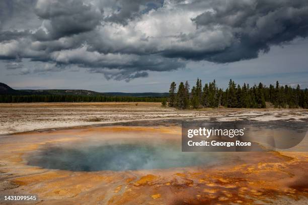 One of the many hot springs in close proximity to the iconic Grand Prismatic Spring in Yellowstone National Park's Midway Geyser Basin is viewed on...