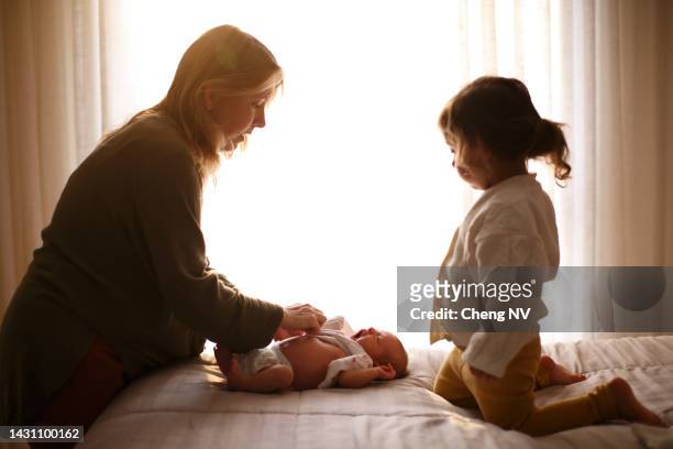 young mother changing her newborn baby in the bedroom - two kids with cycle imagens e fotografias de stock