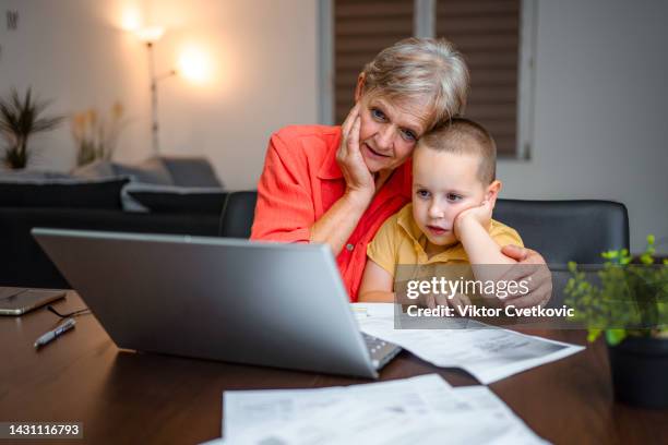 little grandson helping his grandmother with home finance - grandma invoice stock pictures, royalty-free photos & images