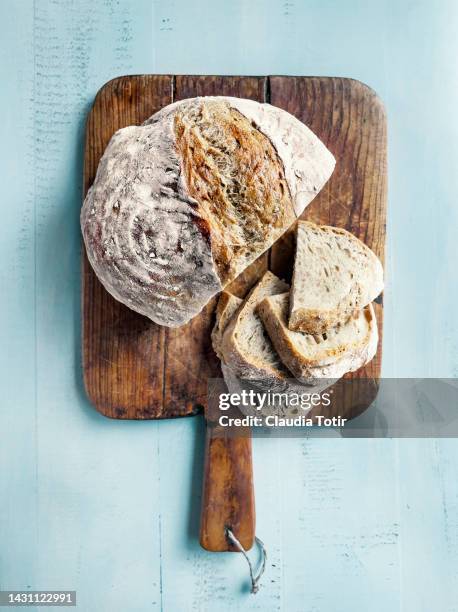 sliced bread on cutting board on blue wooden background - sliced bread stock pictures, royalty-free photos & images