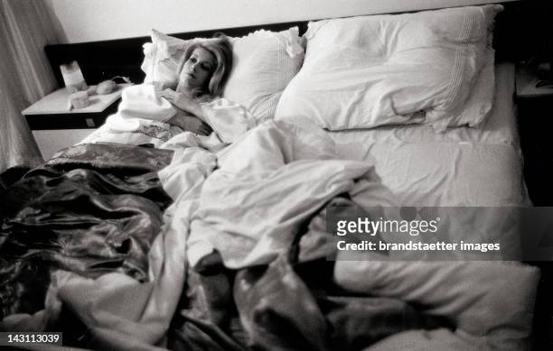 The french actress Catherine Deneuve lying in bed while shooting a movie in Vienna. Austria. Photograph. 1964.