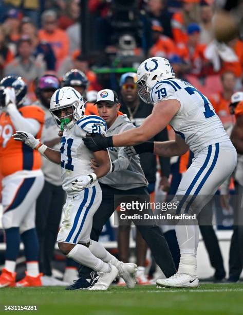 Nyheim Hines of the Indianapolis Colts is helped to his feet by after being hit during a game against the Denver Broncos at Empower Field At Mile...