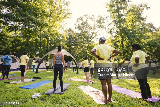 group of women doing yoga at a camping retreat - "marilyn nieves" stock pictures, royalty-free photos & images