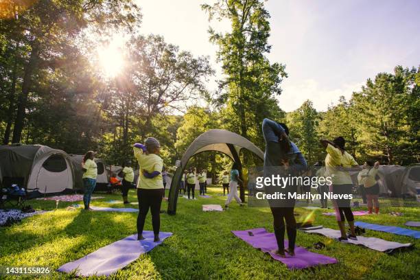 group of women doing yoga at a camping retreat - "marilyn nieves" stock pictures, royalty-free photos & images
