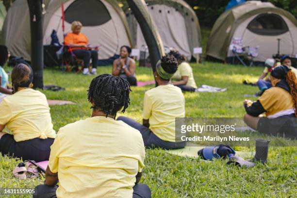 women in campout practicing meditation as a group - "marilyn nieves" stock pictures, royalty-free photos & images