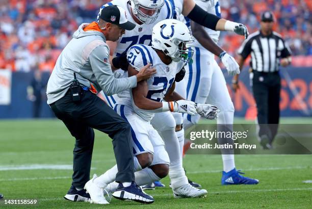 Nyheim Hines of the Indianapolis Colts is helped to his feet by after being hit during a game against the Denver Broncos at Empower Field At Mile...