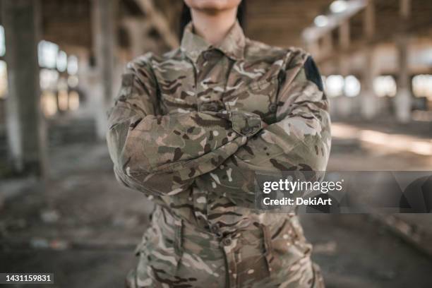 close-up of female soldier in uniform holding crossed arms - military uniform close up stock pictures, royalty-free photos & images