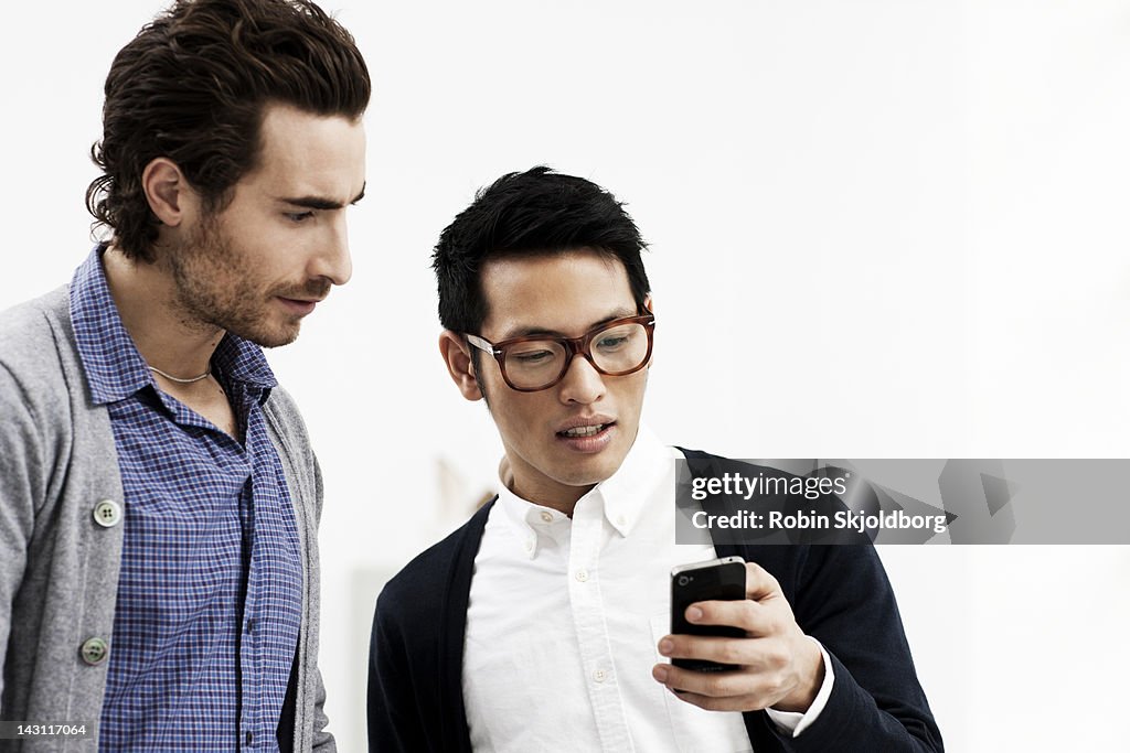 Two creative young men looking at mobile