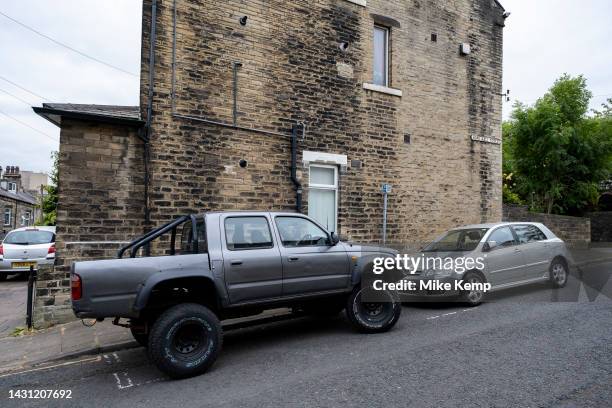 Pickup truck with jacked up suspension and chunky tyres next to a small hatchback car on 6th June 2023 in Halifax, United Kingdom.