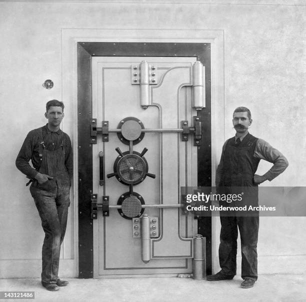 Two workmen stand by a recently completed bank vault door, San Francisco, California, July 6, 1909.