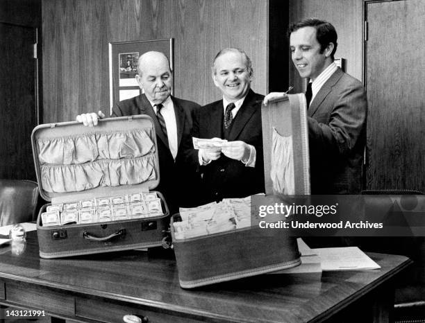 Secret Service agent, the US Attorney, and the District Attorney show off two suitcases of captured counterfeit money, New York, New York, May 8,...