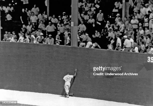 St Louis Cardinal outfielder, Curt Flood, leans against the wall as he symbolizes the frustration of the Cardinals as the fans scramble to get a home...